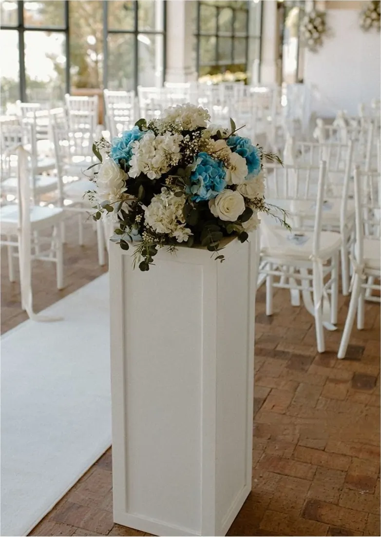 White square plinth with flowers lining a wedding aisle